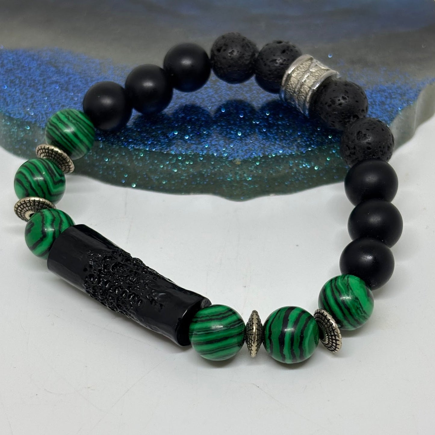 Black and green beaded bracelet on a textured surface