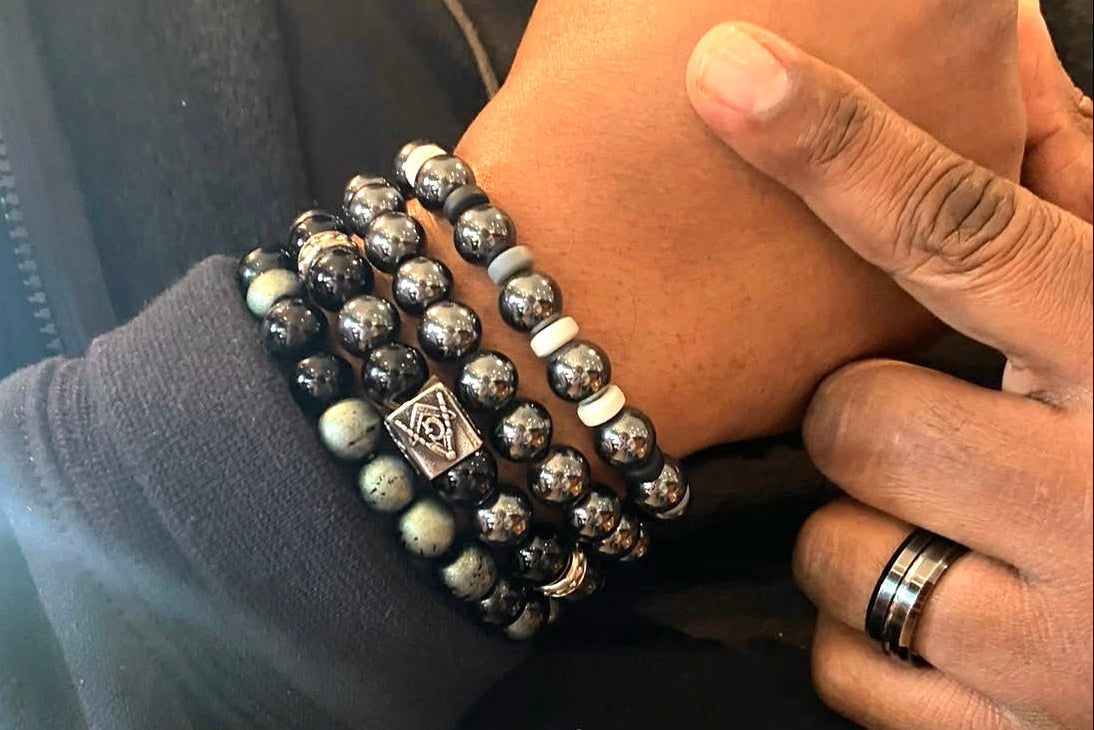 Hand wearing multiple beaded bracelets with a focus on the jewelry.