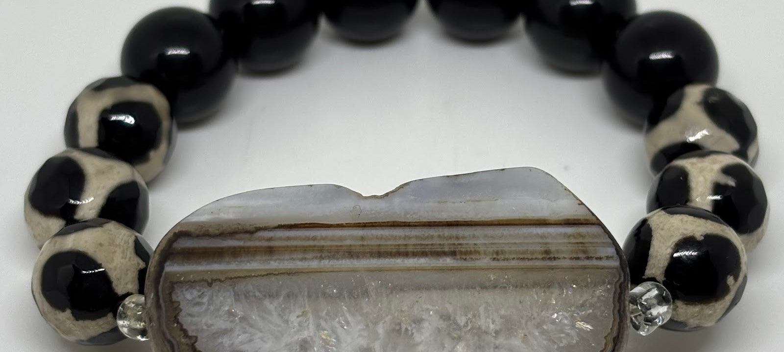 Bracelet with black and white beads and a central stone on a white background