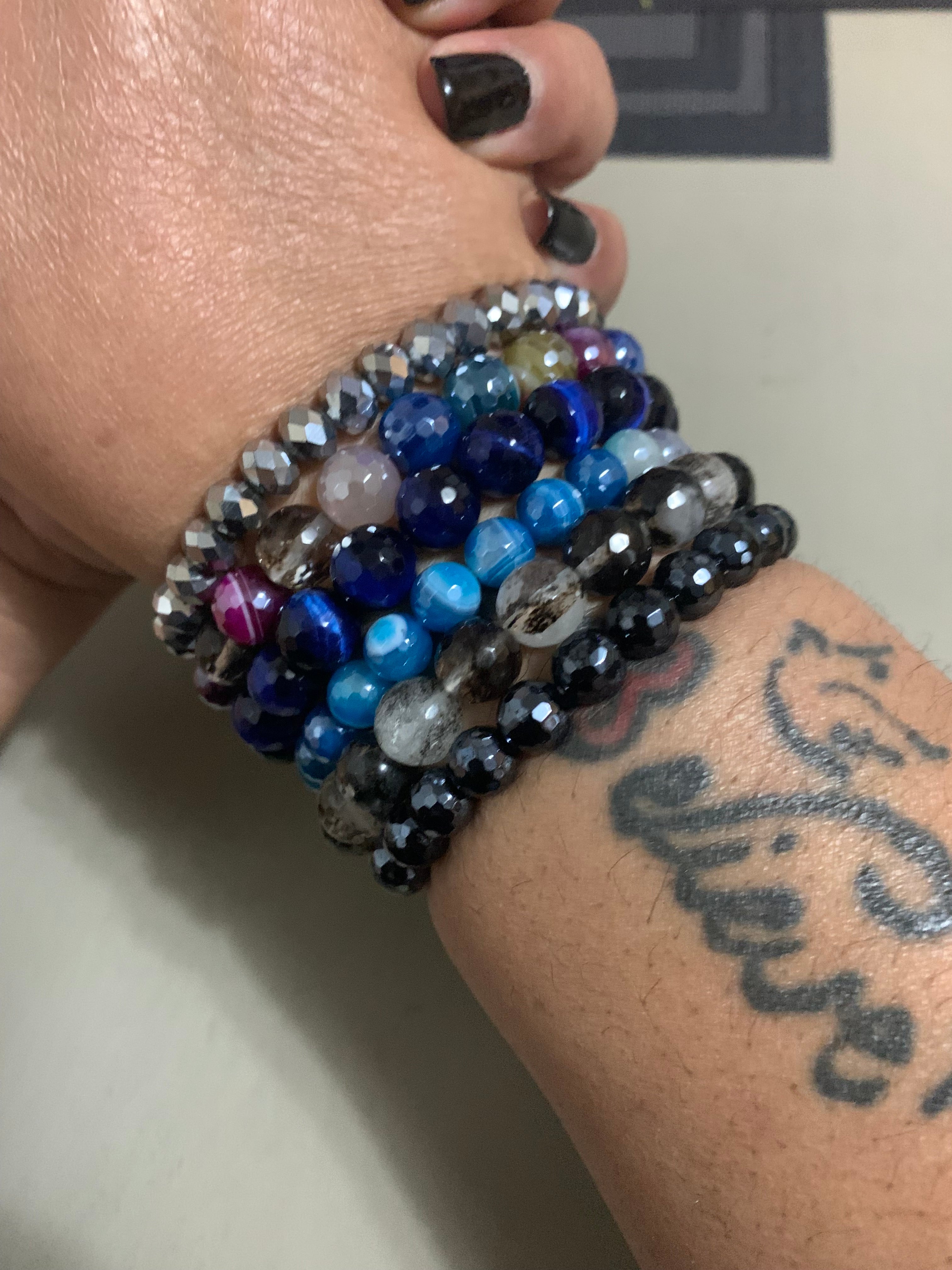 Stack of beaded bracelets on a wrist with tattoos