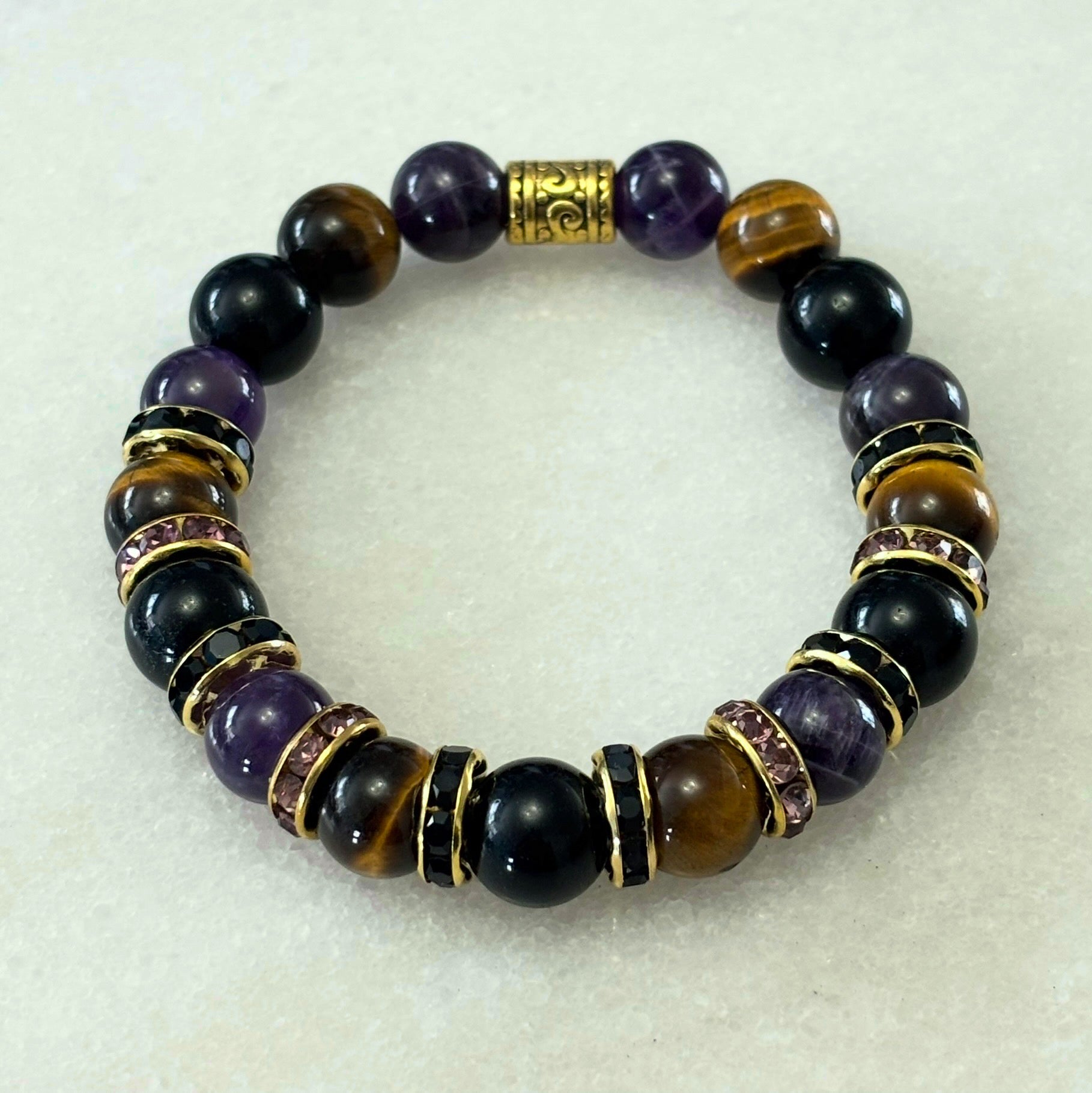 Beaded bracelet with purple, black, and gold beads on a white background