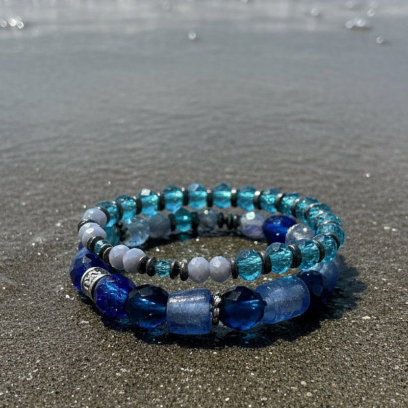 Set of blue and clear beaded bracelets on a black mannequin hand.