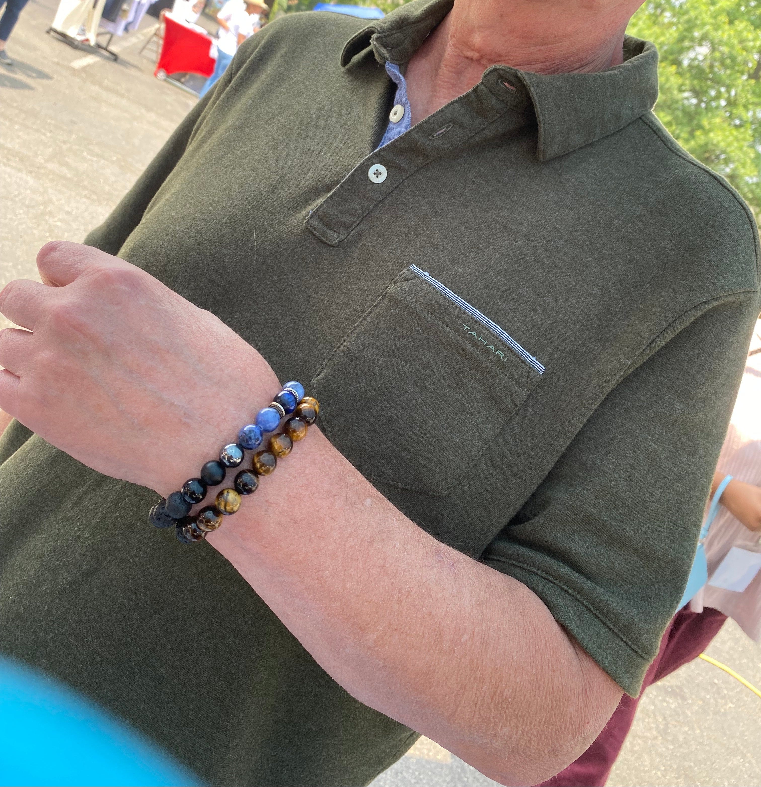 Person wearing a green polo shirt with a blurred outdoor background