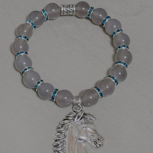 Bracelet with rose quartz beads and a silver horse head charm on a gray background